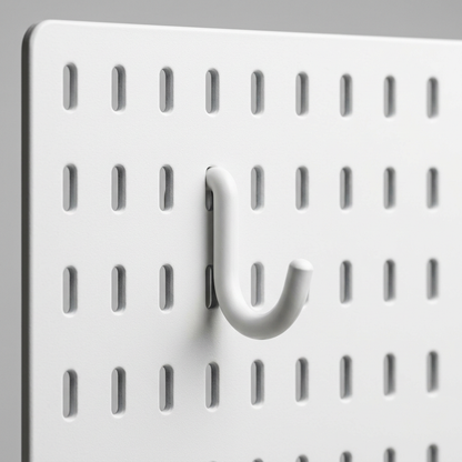 Macro close-up of a white J-hook inserted in the slot holes of a white pegboard panel