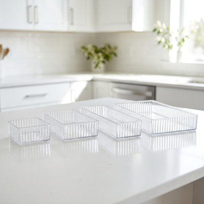 Four clear acrylic organizer bins lined up from small to extra large on a white counter