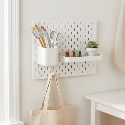 White pegboard panel styled for a craft corner with brushes, tapes and a tote bag