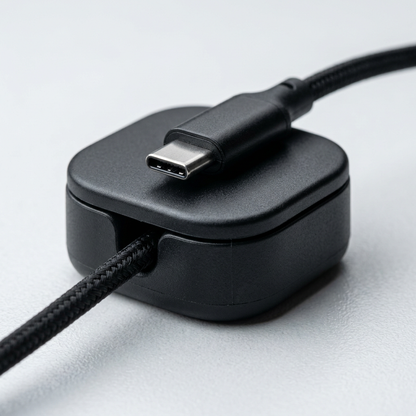 Macro close-up of a matte black magnetic cable clip holding a USB-C cable