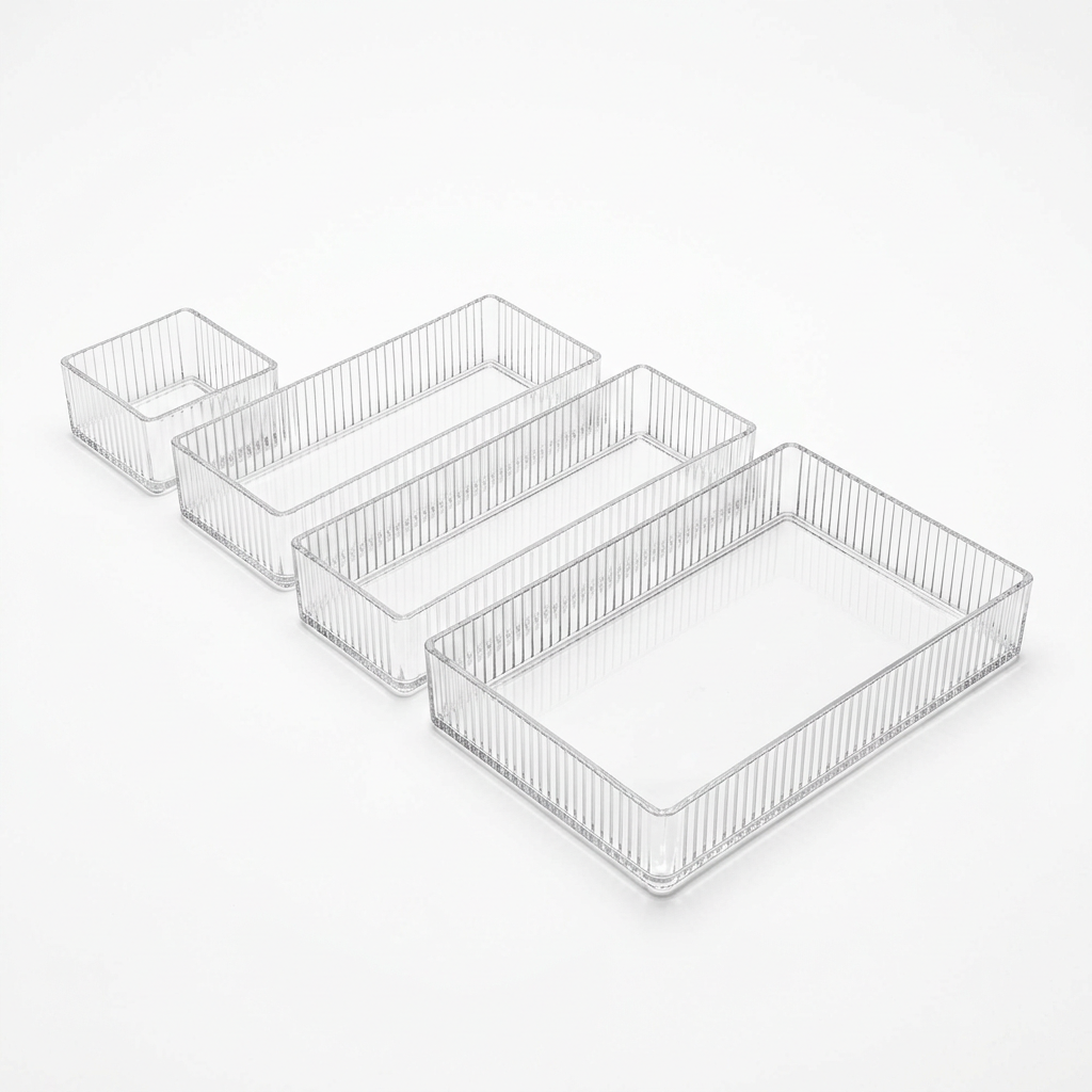 Set of four clear ribbed acrylic drawer organizer bins in four sizes on a white background