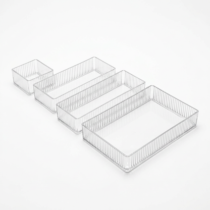 Set of four clear ribbed acrylic drawer organizer bins in four sizes on a white background
