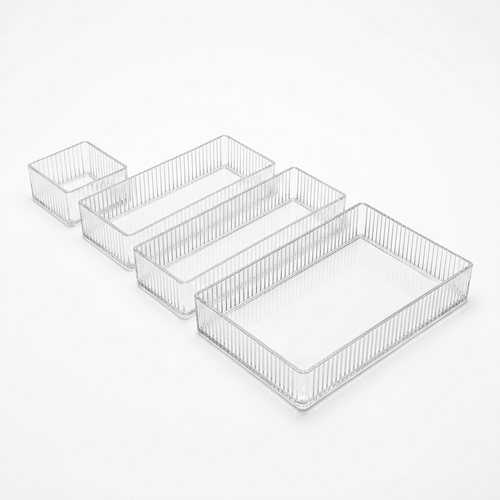 Set of four clear ribbed acrylic drawer organizer bins in four sizes on a white background