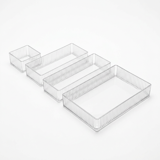 Set of four clear ribbed acrylic drawer organizer bins in four sizes on a white background